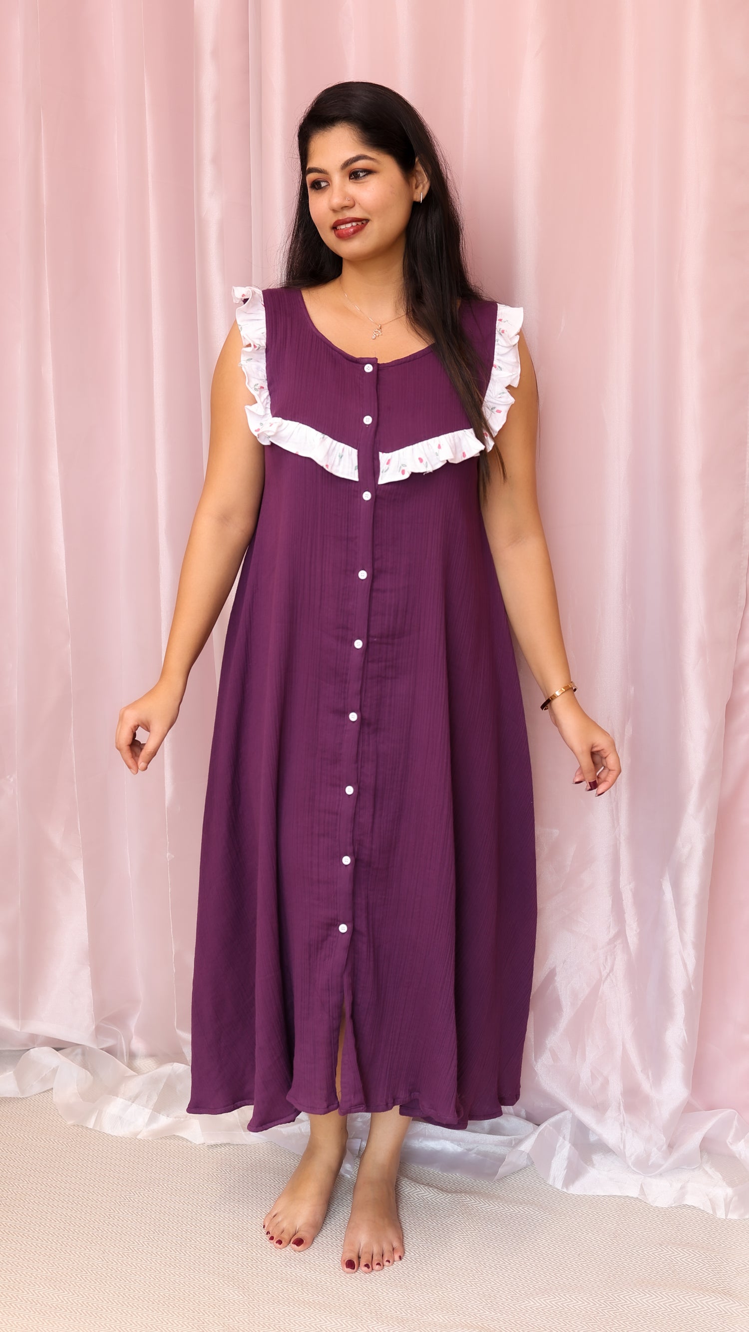 Woman wearing a purple dress with white lace trim against a pink curtain background
