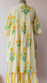 A yellow and white striped dress with green floral prints, displayed on a mannequin in front of a light pink wall.