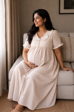 Pregnant woman in a beige dress sitting on a couch in a home setting